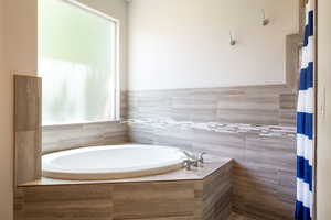 Bathroom featuring a bath and a shower with curtain