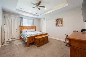 Bedroom featuring a raised ceiling, baseboards, light carpet, and visible vents