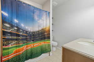 Full bath with vanity, curtained shower, toilet, baseboards, and tile patterned floors