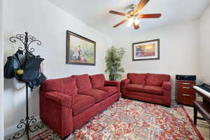 Living room featuring light wood-style floors, a ceiling fan, and baseboards