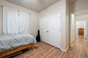 Bedroom featuring a closet, baseboards, visible vents, and light wood-style floors