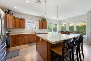Kitchen with brown cabinets, visible vents, a kitchen island, and a sink