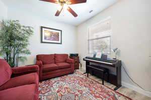 Living room with baseboards, a ceiling fan, light wood finished floors, and visible vents