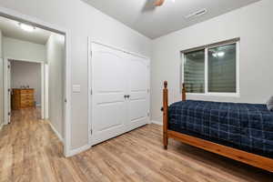 Bedroom featuring ceiling fan, visible vents, baseboards, a closet, and light wood finished floors