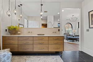 Bathroom with a sink, double vanity, decorative backsplash, and tile patterned floors