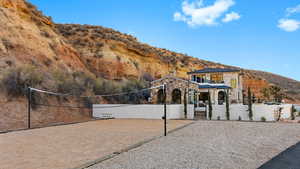 View of front facade featuring fence private yard, a mountain view, volleyball court, and stone siding
