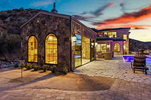 Exterior space featuring stone siding, an outdoor pool, a patio area, and a balcony