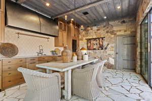 Kitchen featuring brown cabinets, stone flooring, a sink, wooden ceiling, and light countertops