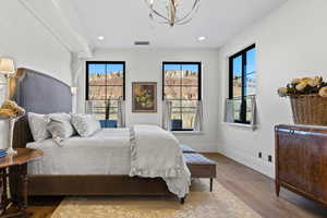 Bedroom with a notable chandelier, recessed lighting, baseboards, wood finished floors, and visible vents