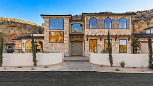View of front of property with fence, a mountain view, and stone siding