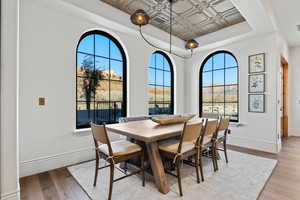 Dining area featuring a tray ceiling, baseboards, and light wood-style floors