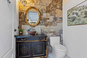 Half bath featuring vanity, baseboards, and toilet