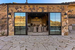 View of exterior entry with a patio and stone siding