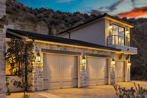 Contemporary home featuring a garage, stone siding, decorative driveway, and a balcony