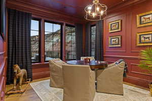 Dining room with a chandelier, ornamental molding, wood finished floors, and a decorative wall