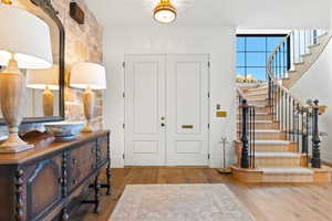 Foyer with stairs, baseboards, and wood finished floors