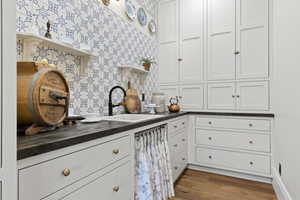 Kitchen featuring a sink, open shelves, wood finished floors, and white cabinetry