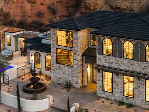 View of front facade featuring a patio area, stucco siding, a balcony, and stone siding