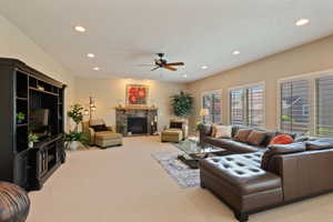 Living area featuring light colored carpet, recessed lighting, a ceiling fan, and a fireplace