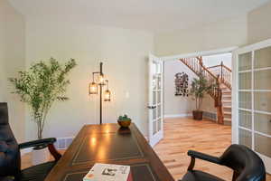 Office space featuring french doors, light wood-style floors, baseboards, and visible vents