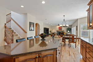 Kitchen with a fireplace, light wood-style floors, open floor plan, recessed lighting, and a sink