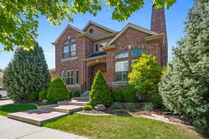 Traditional-style home with brick siding, a chimney, and a front yard