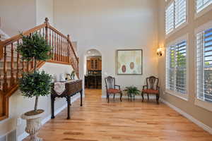 Interior space featuring a towering ceiling, stairs, baseboards, light wood-type flooring, and visible vents