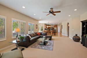 Living area featuring recessed lighting, a ceiling fan, light colored carpet, and baseboards
