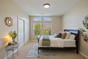 Bedroom featuring light colored carpet, baseboards, visible vents, and a closet