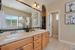 Bathroom featuring tile patterned flooring, a sink, a stall shower, and double vanity