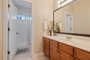 Bathroom featuring baseboards, a shower with door, tile patterned floors, and vanity