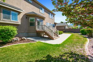Back of property with stucco siding, a patio area, fence, and a lawn