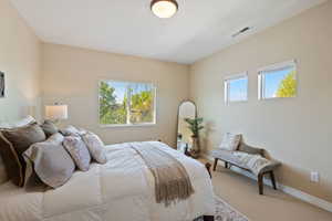 Carpeted bedroom featuring baseboards and visible vents