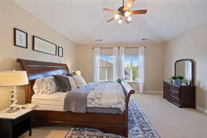 Bedroom with light colored carpet, baseboards, vaulted ceiling, and visible vents