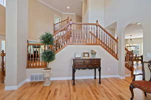 Stairs featuring a high ceiling, wood finished floors, and visible vents