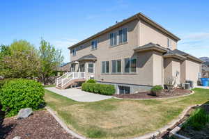 Back of house with stucco siding, a yard, and central AC