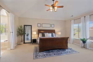 Bedroom featuring visible vents, arched walkways, vaulted ceiling, baseboards, and carpet