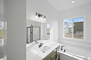 Full bathroom with vanity, a shower stall, a garden tub, and lofted ceiling