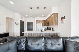 Kitchen with open floor plan, a peninsula, brown cabinets, and stainless steel appliances