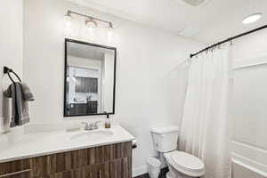 Bathroom featuring vanity, shower / tub combo, and toilet
