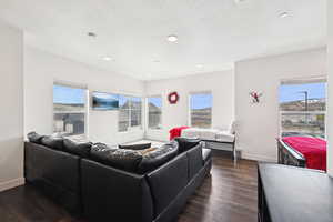 Living area with recessed lighting, baseboards, dark wood-style flooring, and a textured ceiling