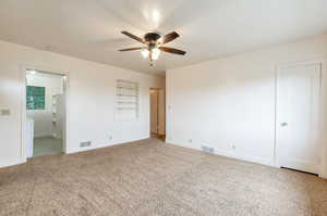 Unfurnished bedroom with carpet flooring, baseboards, visible vents, and ensuite bath