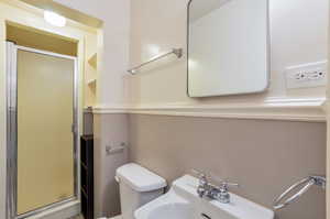 Full bathroom featuring a sink, a stall shower, and toilet