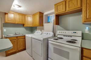 Washroom featuring laundry area, a sink, a textured ceiling, and washer and dryer