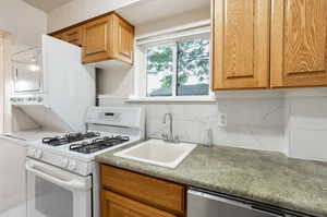 Kitchen featuring brown cabinets, a sink, dishwasher, decorative backsplash, and white range with gas stovetop