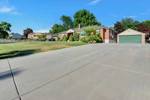 Ranch-style house with a chimney, a garage, brick siding, fence, and a front lawn