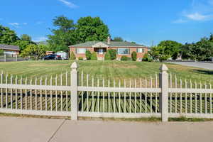 View of front of house featuring brick siding, a fenced front yard, a chimney, and a front lawn