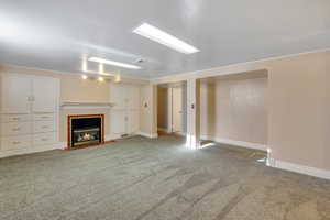 Unfurnished living room featuring carpet floors, baseboards, a tile fireplace, and visible vents