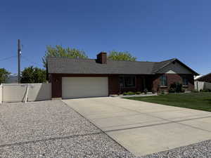 Ranch-style house featuring fence, an attached garage, a front lawn, brick siding, and concrete driveway