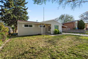 View of front facade featuring a patio, fence, a front yard, and a carport